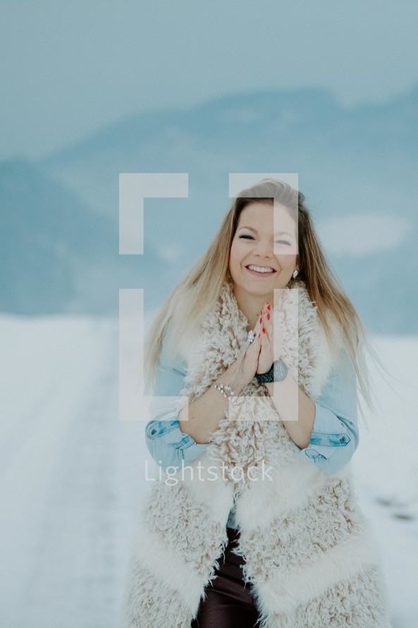 happy woman in a vest standing outdoors in the snow 