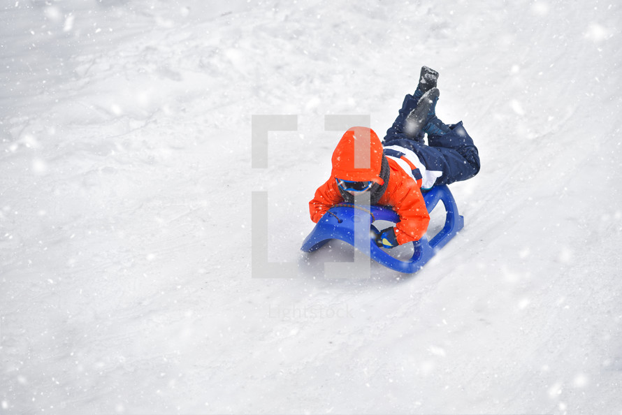 boy riding on snow slides in winter time