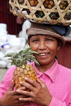 a woman holding a pineapple with a basket on her head 