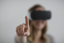 A woman wearing VR glasses and pointing 