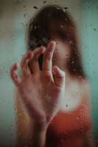 woman's hand touching wet glass 
