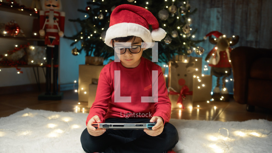 Child playing videogames under the Christmas tree