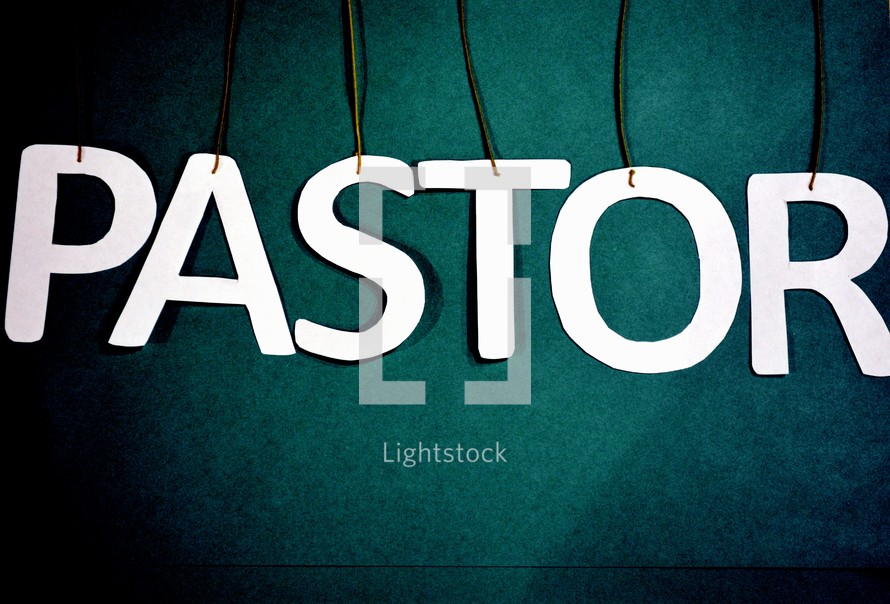 Letters spelling the word, "pastor," suspended from strings.