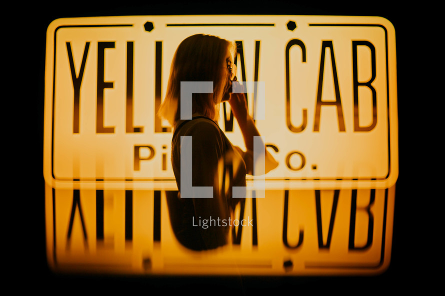 a woman standing in front of a yellow cab sign 
