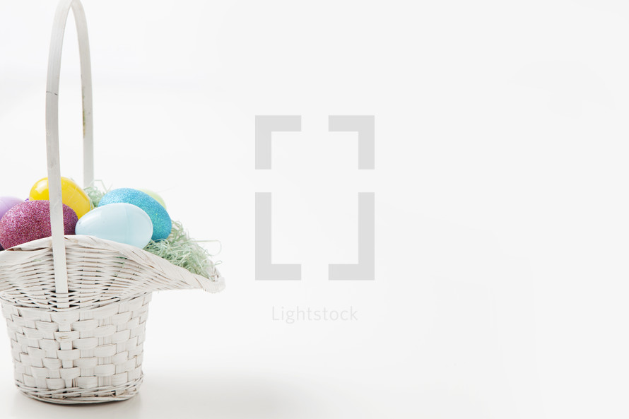 Easter eggs in a basket against a white background.