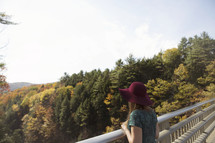woman looking over a railing at a mountain fall forest 