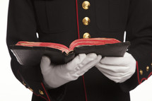 Marine in uniform holding an open Bible.