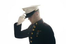 Marine in uniform, adjusting his cover. 