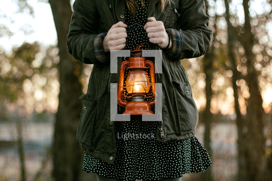 a torso of a woman holding a lantern 