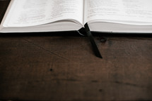 edge of an open Bible on a wooden desk 