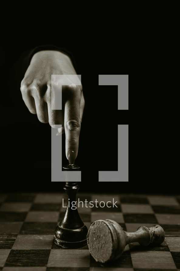 Woman player playing board intelligence game - wooden chess. Close- up view of female arm with red nails moves a chess piece pawn, first move. Sport, success strategy concept. High quality