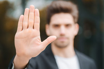 Portrait of young businessman disapproval gesture with hand: denial sign, no sign, negative gesture closes the camera with hand, professional male manager wearing suit jacket