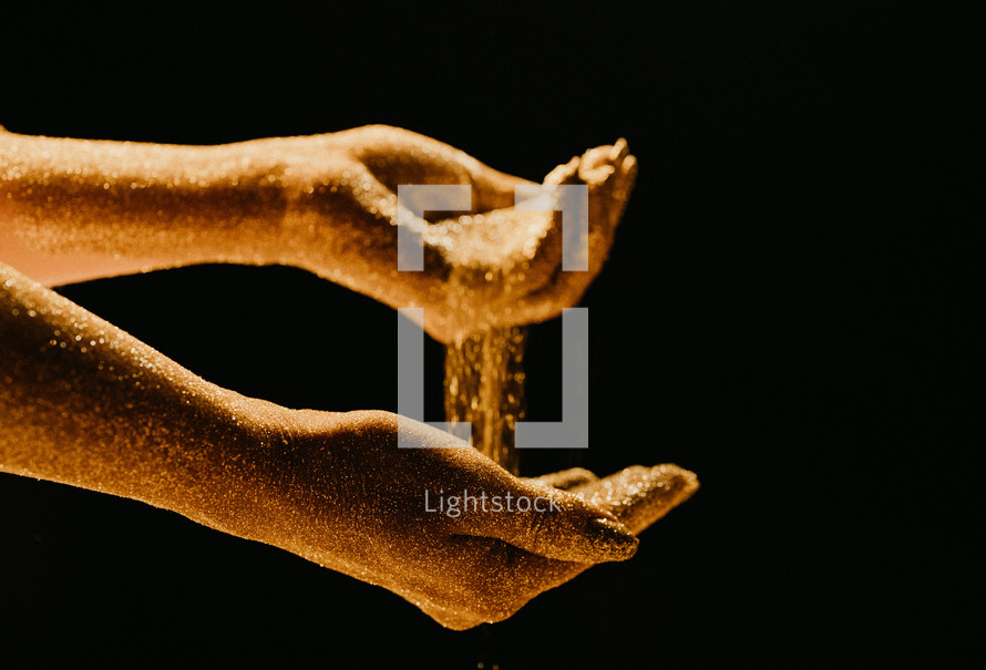 Golden glittering woman hands with dust or sand on black background. Shimmer, time, life moments, deadline, business management, educational creative content concept.