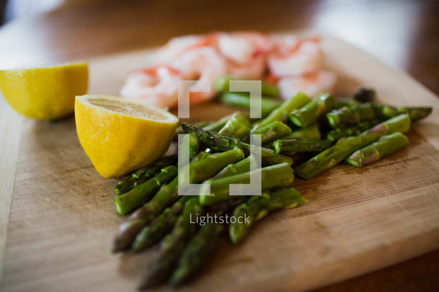 lemons, asparagus, and shrimp on a wood cutting board