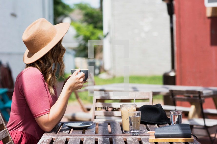 a woman sitting at an outdoor table with coffee waiting on a friend 