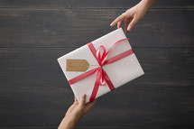 A wrapped gift being given from one person to another.