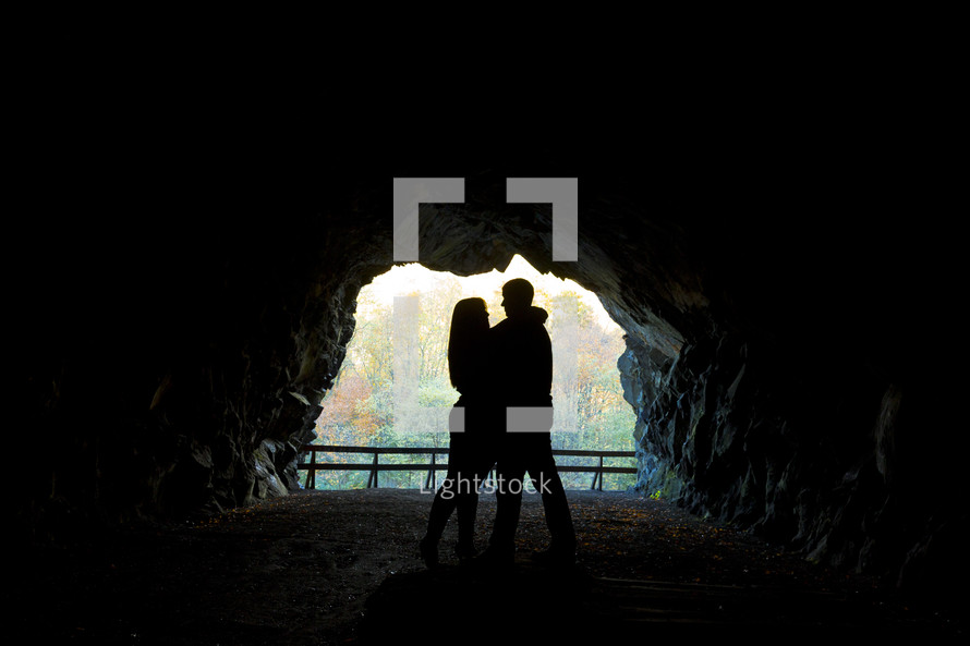 Silhouette of embracing couple standing inside a cave.