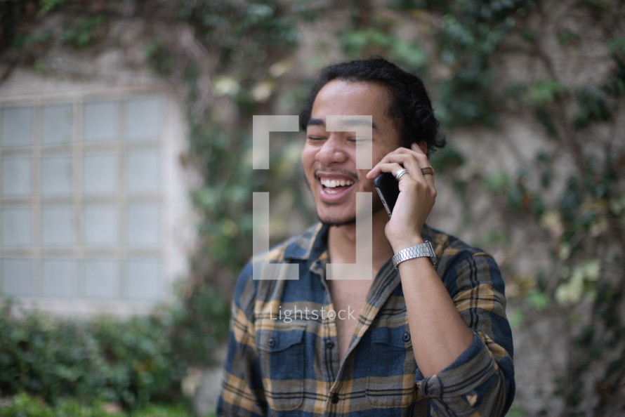 a young man talking on a cellphone outdoors 