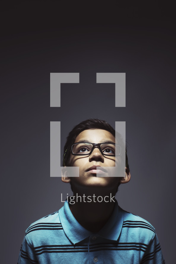 Young kid with glasses looking up.