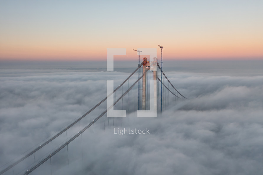 Aerial footage of bridge peeking out from clouds