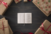 An open Bible surrounded by wrapped gifts.