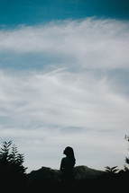 a silhouette of a woman looking up 