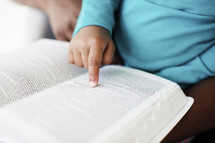 Little girl pointing to a verse in the Bible. 