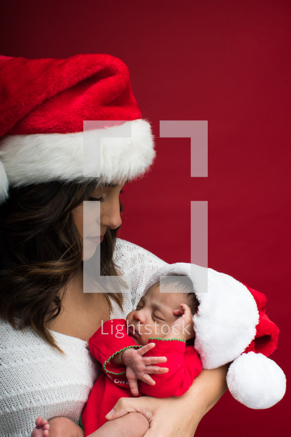 a mother in a Santa hat holding a newborn baby 