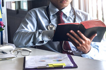 A doctor reading a Bible at his desk during a break