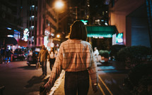 a young woman walking in a city downtown area at night 