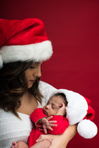 a mother in a Santa hat holding a newborn baby 