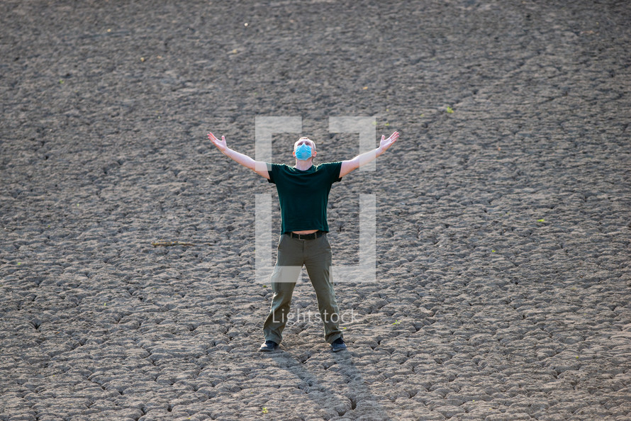 Man raises his hands and praying for rain in dry land