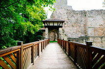 A wooden foot bridge leading to a stone building.