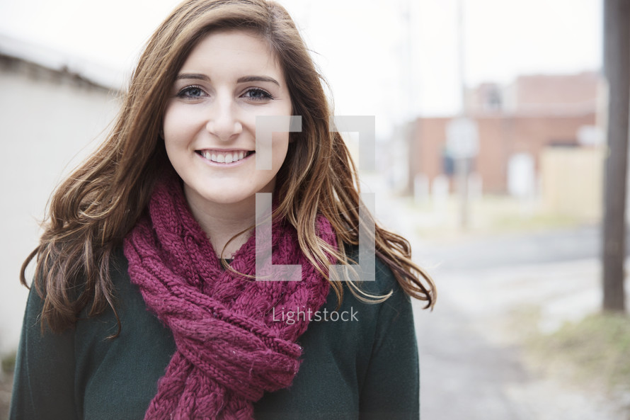 a smiling young woman wearing a scarf