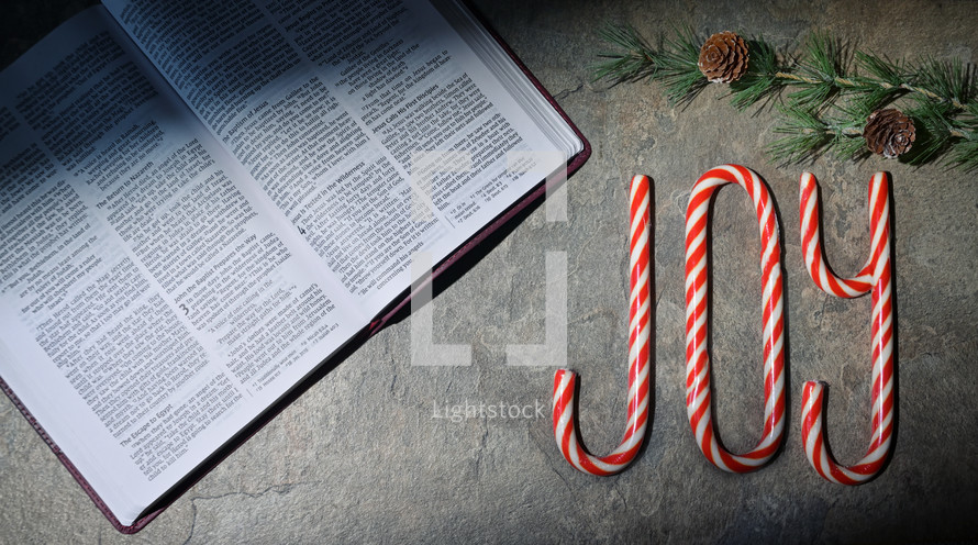 Candy canes spelling joy next to Bible
