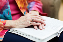 senior woman with hands on a Bible 