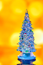 Miniature transparent Christmas tree isolated on golden bokeh light