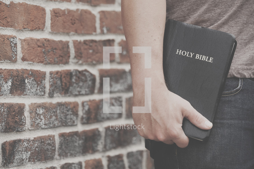 man holding a Holy Bible to his side