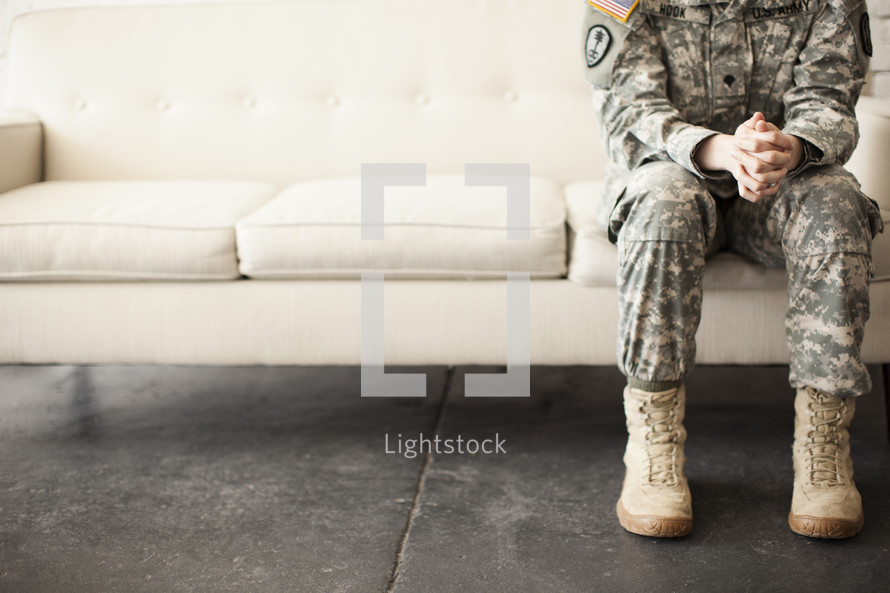 soldier sitting on a couch praying