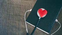 stethoscope and red felt heart on a Bible 