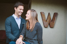 Couple embracing standing against a wall with a large W on the wall