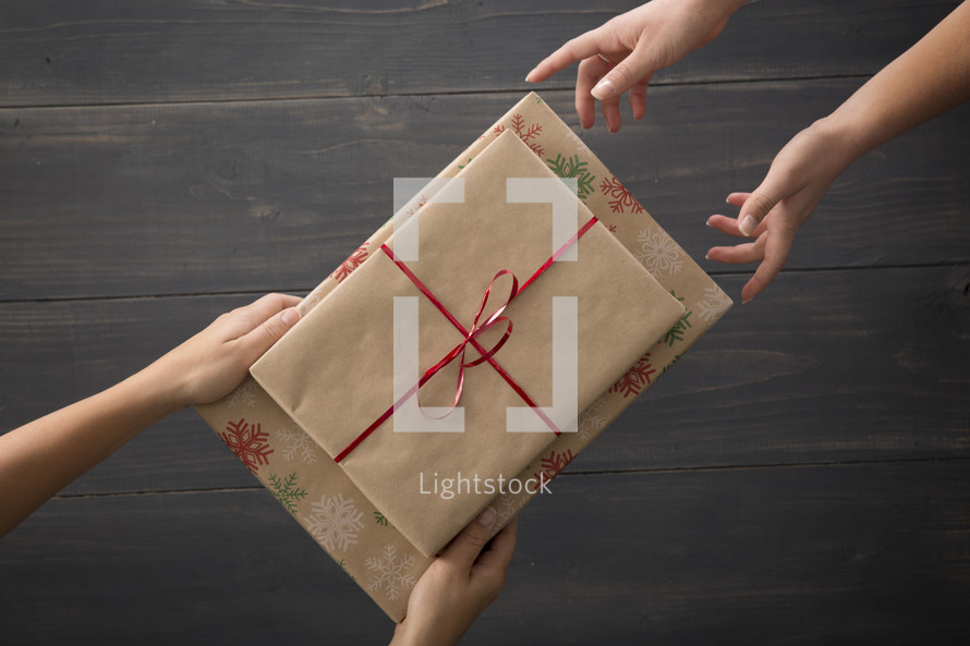 One person giving a wrapped gift to another.
