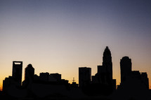 Silhouette of city skyline at sunset.