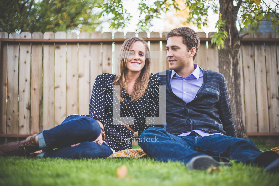 young couple sitting in the grass on a blanket 