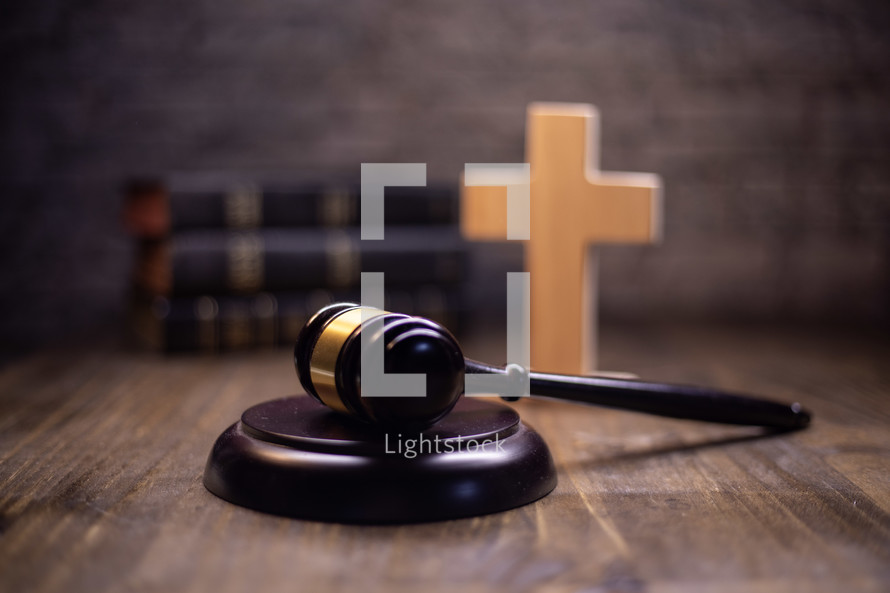 A gavel with a bible and illuminated cross in the background