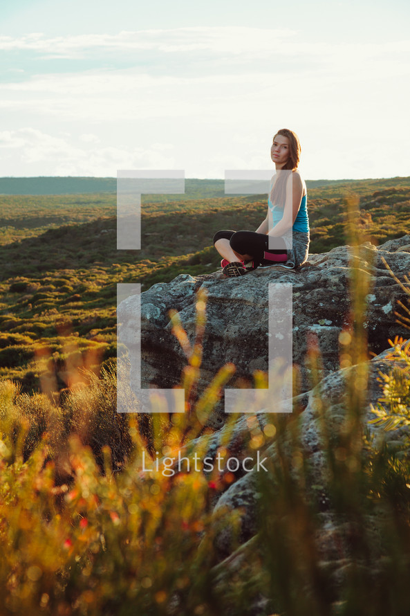 a woman sitting on rock on a mountaintop 