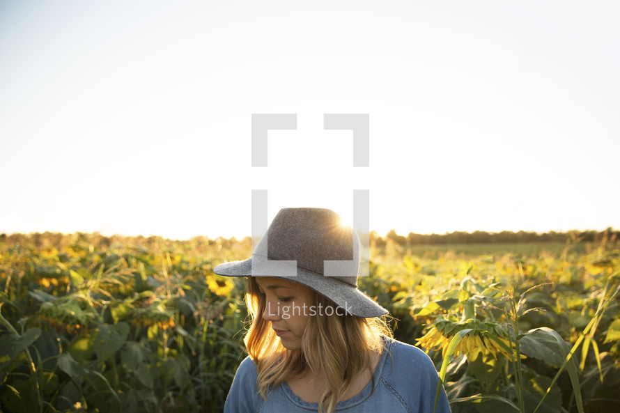 a woman standing in a field of sunflowers under a blue sky 