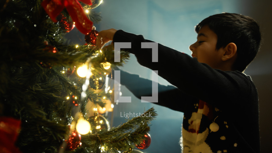 Kid preparing tree for Christmas with decorations