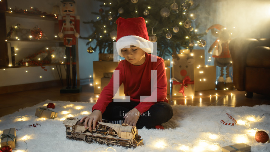 boy with Christmas hat playing with toy train