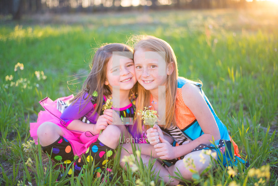 sisters sitting in the grass outdoors 